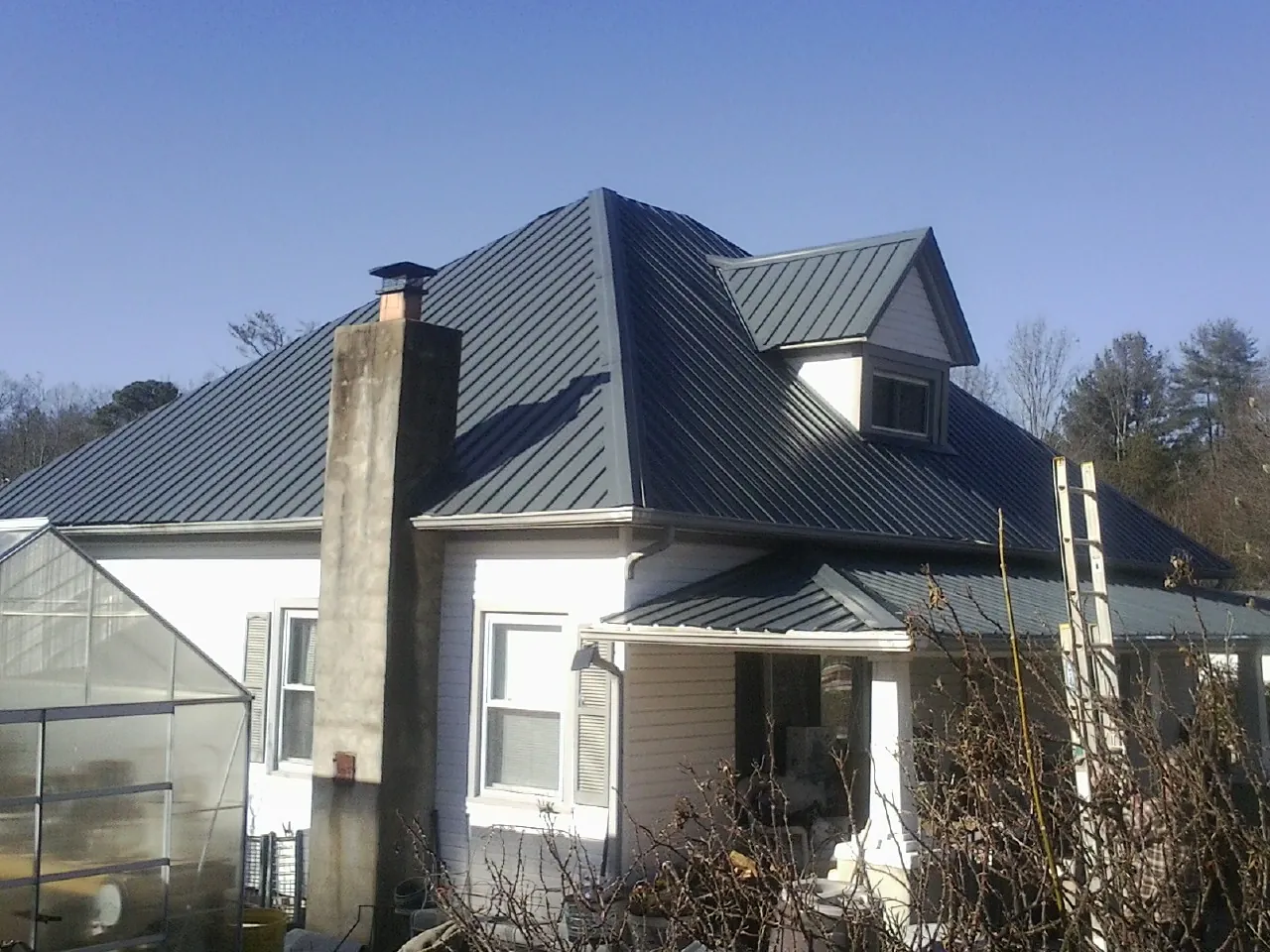 Dark blue standing seam metal roof on a white farmhouse with dormer — Slate & Tile Roof Repair by Roofing Brothers in Ellenville