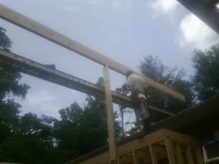 Carpenter setting a ridge beam over a new addition frame — Ice Dam Removal by Roofing Brothers in Ellenville