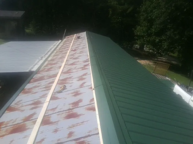 Old rusted panels beside newly installed green metal roofing — Wind Damage Roof Repair by Roofing Brothers in Ellenville