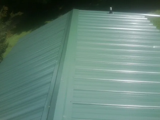 New green metal panels meeting at the ridge of a roof — Flat Roof Repair work by our crew in Ellenville