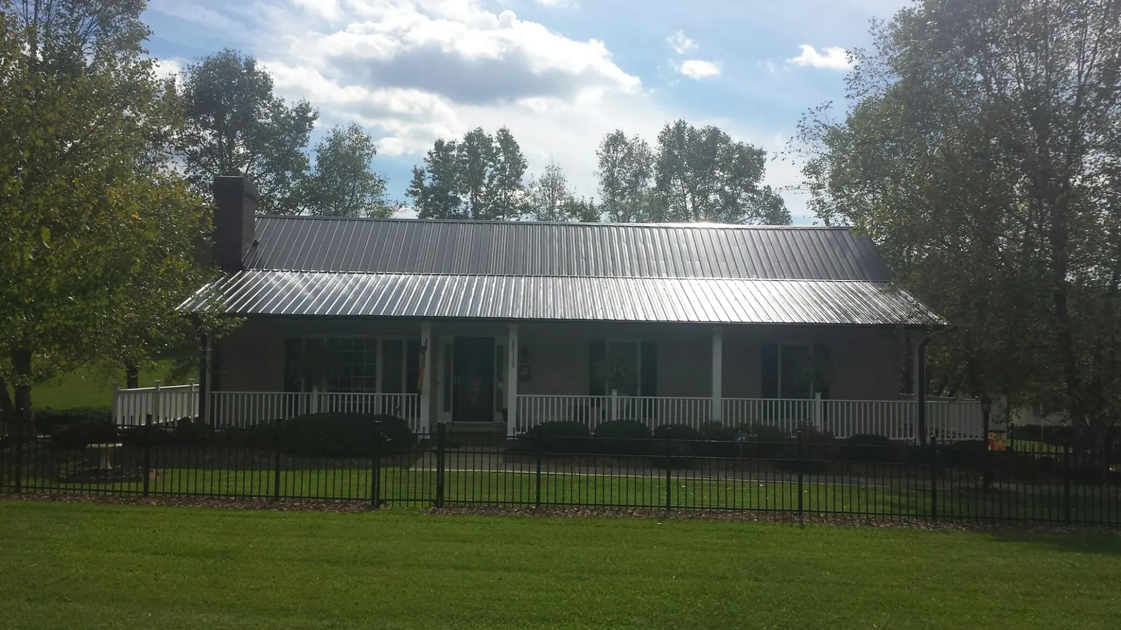 Gray metal roof on a brick ranch with a full width front porch — Gutter Guard Installation work by our crew in Ellenville