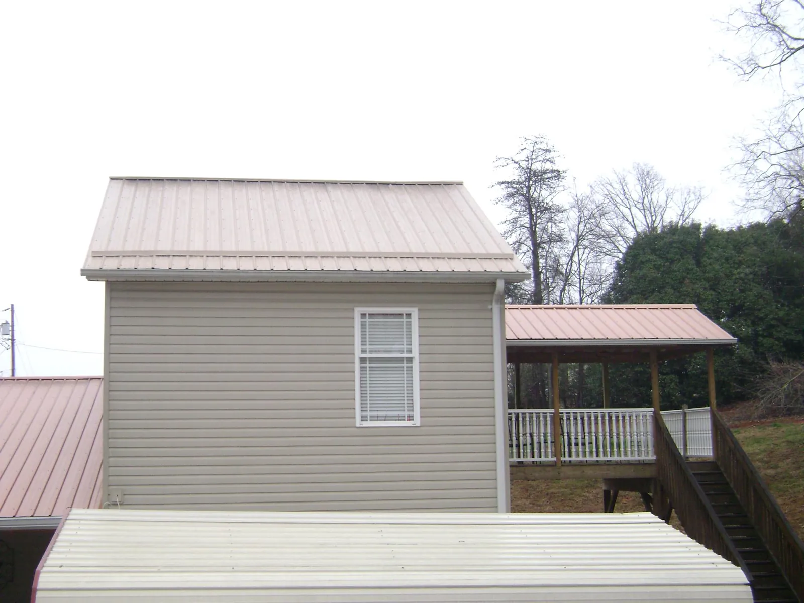 Tan metal roofs on a two story addition and attached porch, from a Roof Replacement job in Ellenville