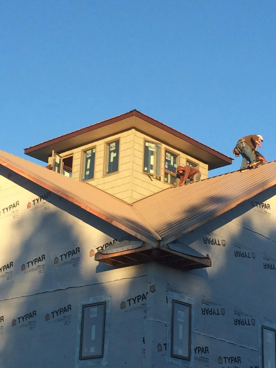 Roofers working around a rooftop cupola on a new metal roof at sunset — Roof Waterproofing in Ellenville by Roofing Brothers
